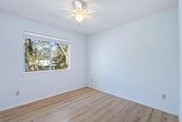 a view of empty room with wooden floor and fan