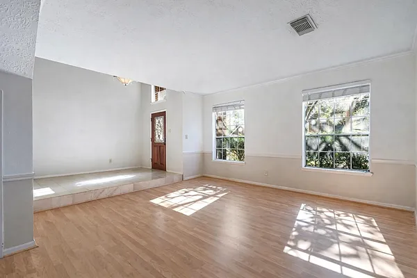 a view of an empty room with window and wooden floor