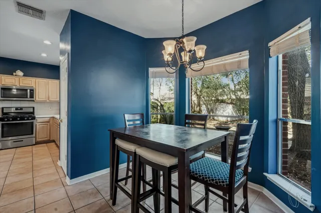 a dining room with wooden floor a chandelier a wooden table and chairs