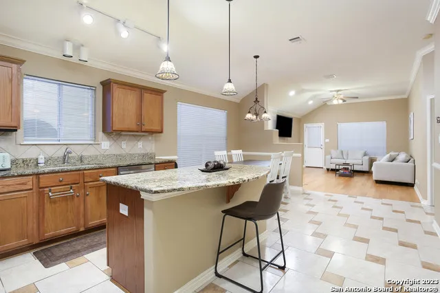 a kitchen with stainless steel appliances granite countertop a sink a stove and a wooden cabinets