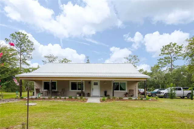 a front view of a house with swimming pool and porch with furniture