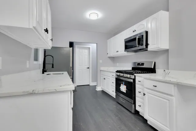 a kitchen with stainless steel appliances granite countertop white cabinets a microwave oven a sink and dishwasher with wooden floor