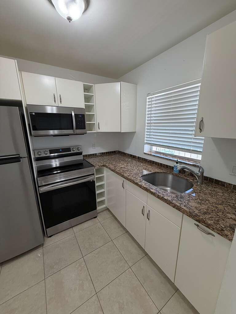 a kitchen with granite countertop a stove sink and cabinets