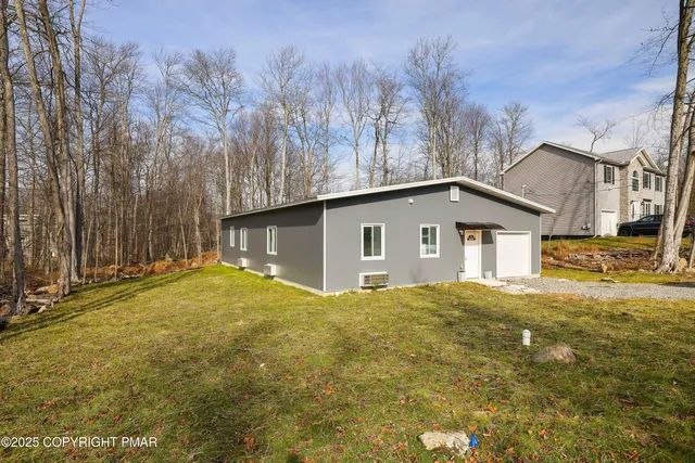a view of a house with a yard and large tree