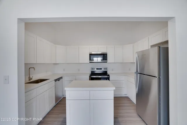 a kitchen with a sink a refrigerator and white cabinets