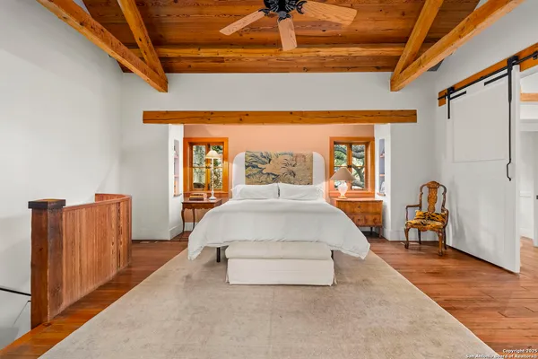 a spacious bedroom with a bed and wooden floor