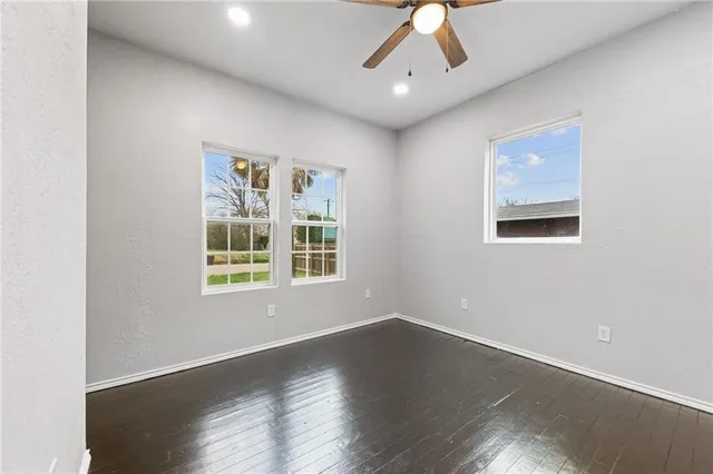 an empty room with wooden floor chandelier and windows