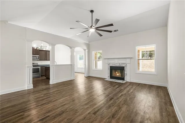 an empty room with wooden floor fireplace and windows