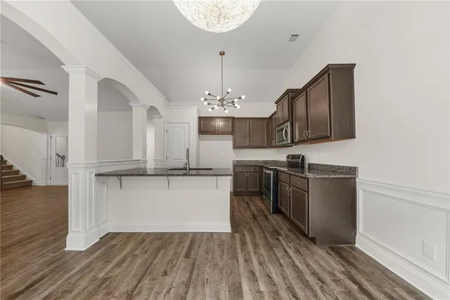 a kitchen with stainless steel appliances granite countertop a sink cabinets and wooden floor