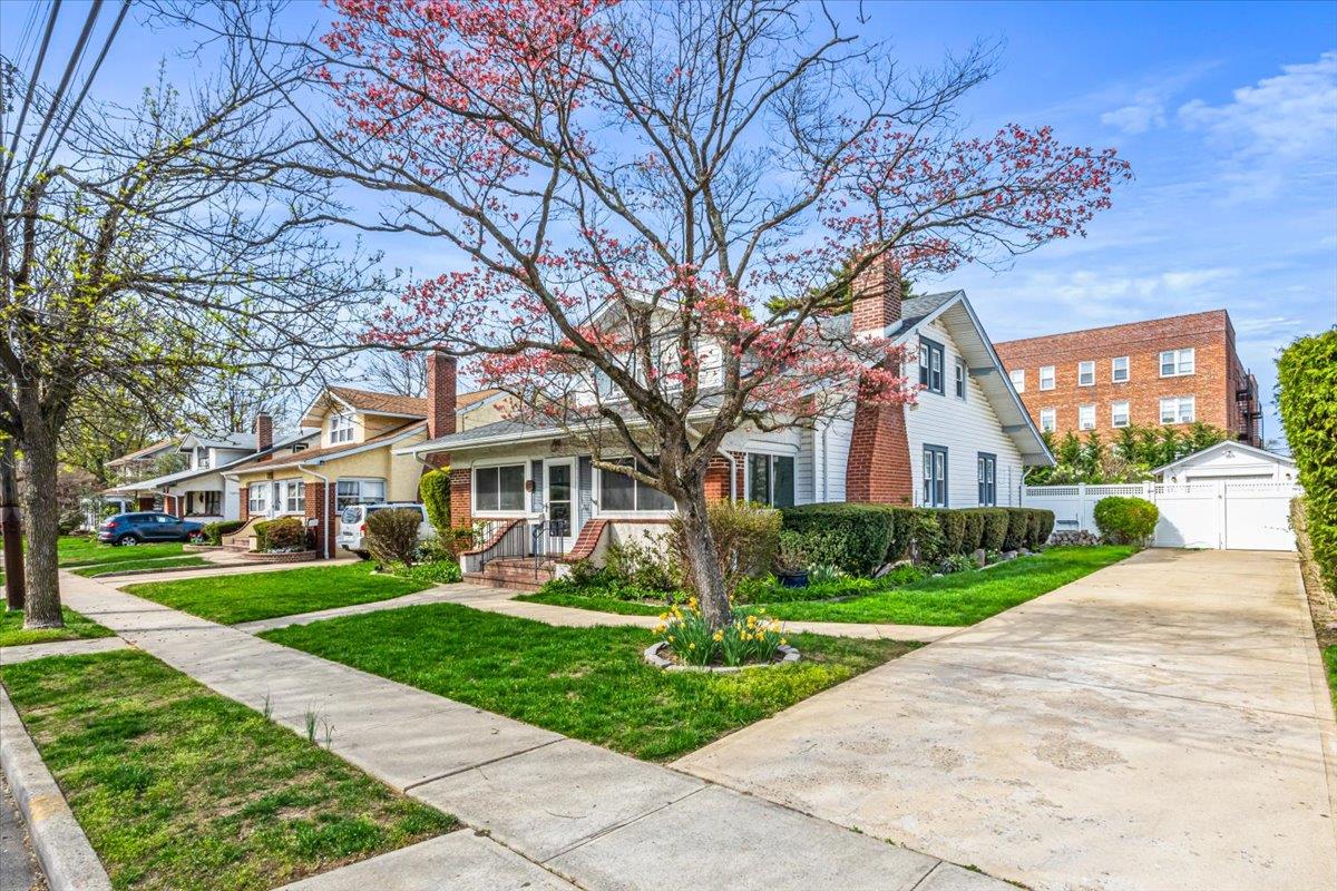 View of front facade with a residential view, a chimney, a front yard, fence, and brick siding