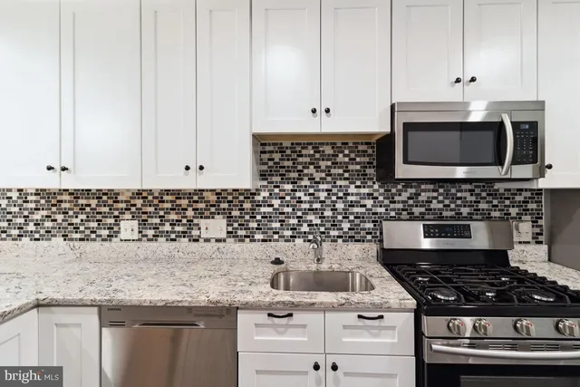 a kitchen with granite countertop white cabinets and stainless steel appliances