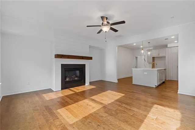 a view of a livingroom with a fireplace a ceiling fan and a kitchen