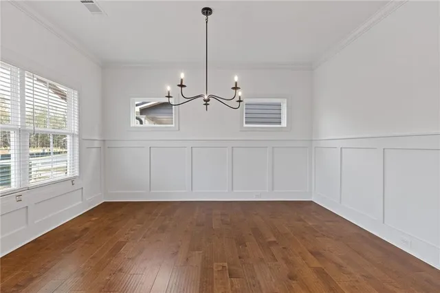 a view of an empty room with wooden floor windows