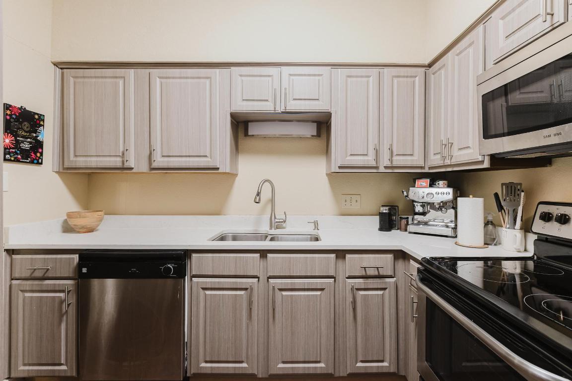 1910 Robbins Place, Unit 207 Austin, TX 78705 - Photo 6 of 28 a kitchen with stainless steel appliances granite countertop a sink stove and microwave