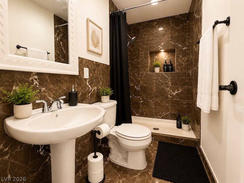 3010 East Viking Road Las Vegas, NV 89121 - Photo 28 of 48 Luxurious brown marble tiles adorn this modern bathroom, featuring a sleek pedestal sink and a spacious shower.