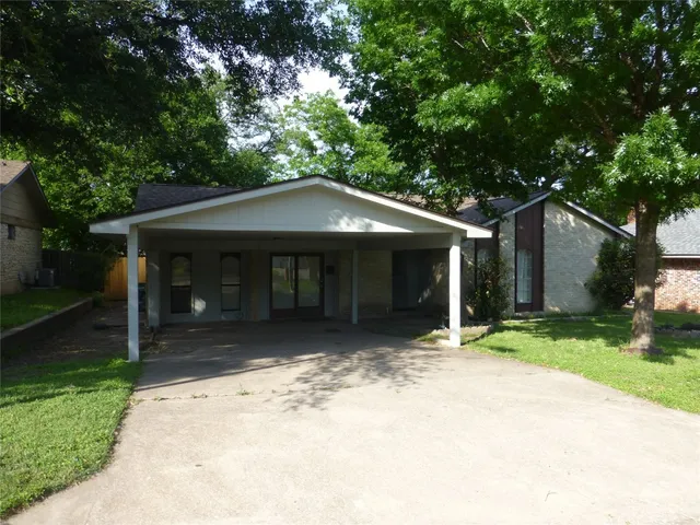 a front view of a house with a garden and trees