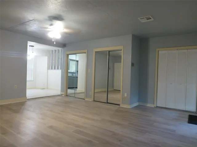an empty room with wooden floor mirror and windows