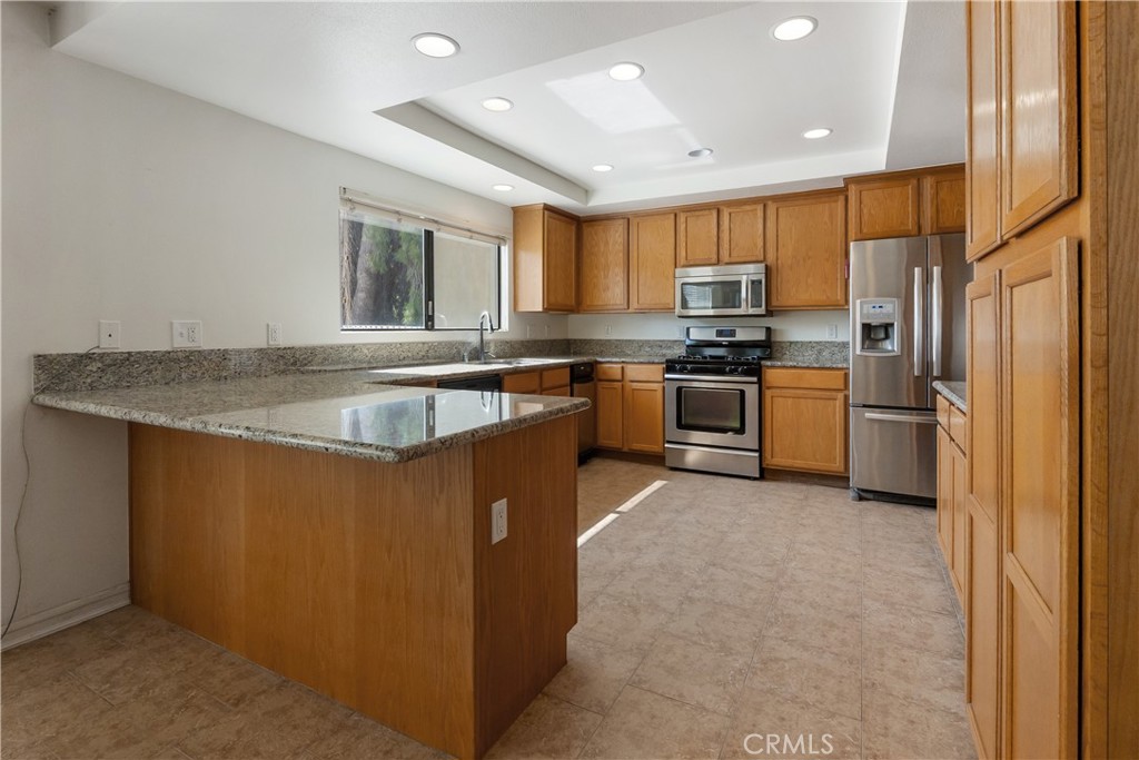 17656 Mockingbird Hill Circle Riverside, CA 92504 - Photo 10 of 49 a kitchen with stainless steel appliances granite countertop a stove top oven a sink and a refrigerator