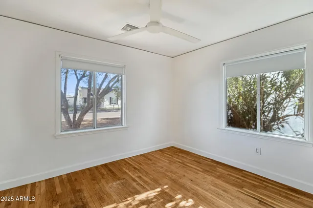 a view of empty room with wooden floor and fan