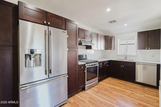 a kitchen with stainless steel appliances granite countertop a refrigerator stove and sink