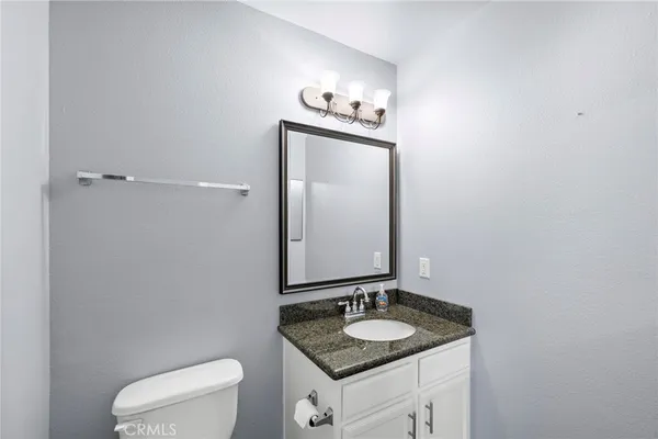 a bathroom with a granite countertop sink vanity mirror and toilet
