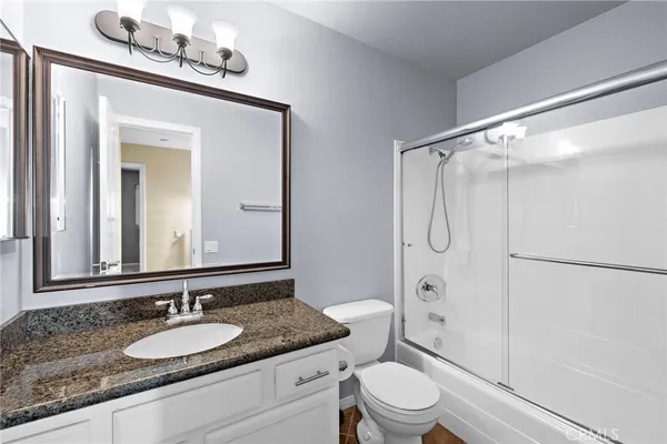 a bathroom with a granite countertop sink toilet mirror and shower