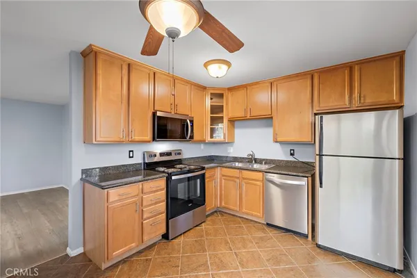 a kitchen with stainless steel appliances granite countertop a stove a sink dishwasher a refrigerator and a microwave oven with cabinets