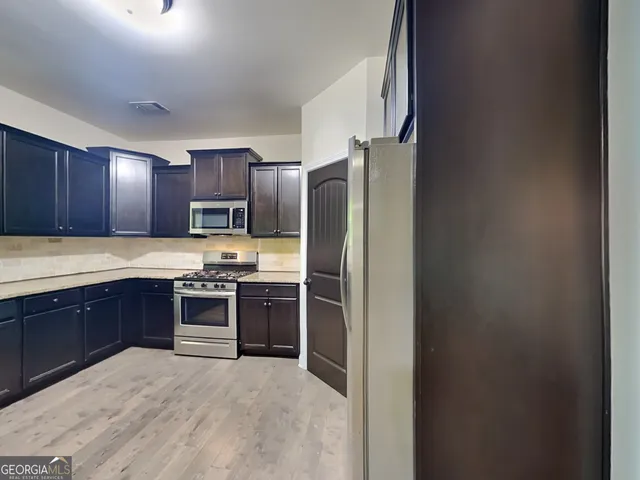 a large kitchen with stainless steel appliances granite countertop a refrigerator stove and sink