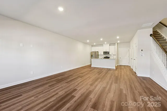 a view of kitchen and empty room with wooden floor