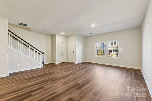 a view of an empty room with wooden floor and stairs
