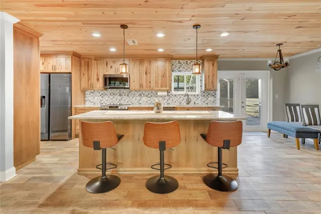 a large kitchen with kitchen island a stove a sink a dining table and chairs with wooden floor