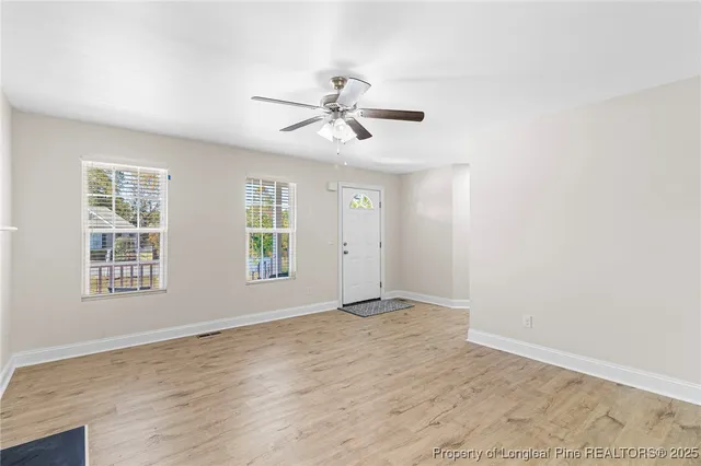 a view of empty room with wooden floor and fan