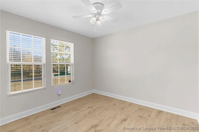 an empty room with a window and a fan