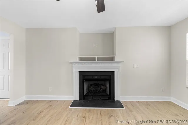 a view of an empty room with wooden floor and a fireplace