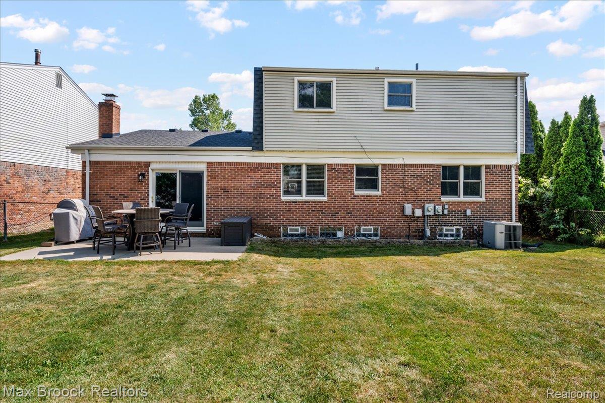 42470 Bishop Road Canton, MI 48188 - Photo 30 of 37 Expansive grassy yard with a concrete patio, brick and siding exterior, and a prominent brick chimney