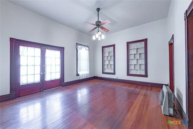 a view of an empty room with wooden floor and a window