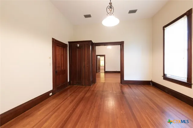 an empty room with wooden floor and windows