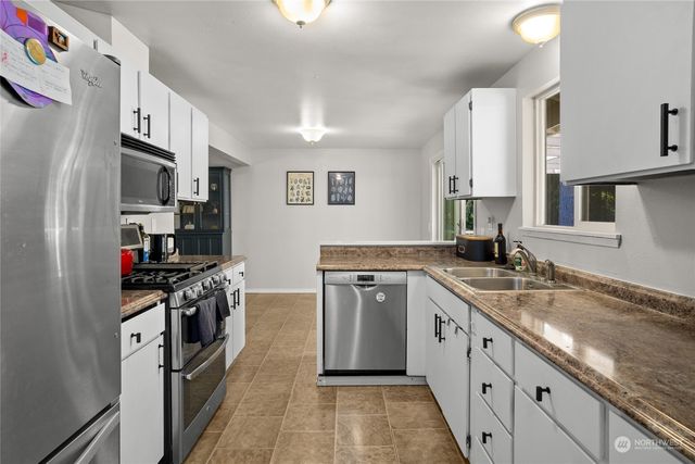 a kitchen with stainless steel appliances granite countertop a sink stove refrigerator and cabinets