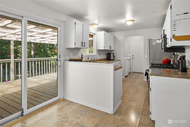 a kitchen with stainless steel appliances kitchen island granite countertop a stove a sink and white cabinets