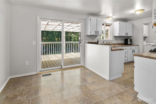 a kitchen with kitchen island granite countertop a stove a sink and white cabinets