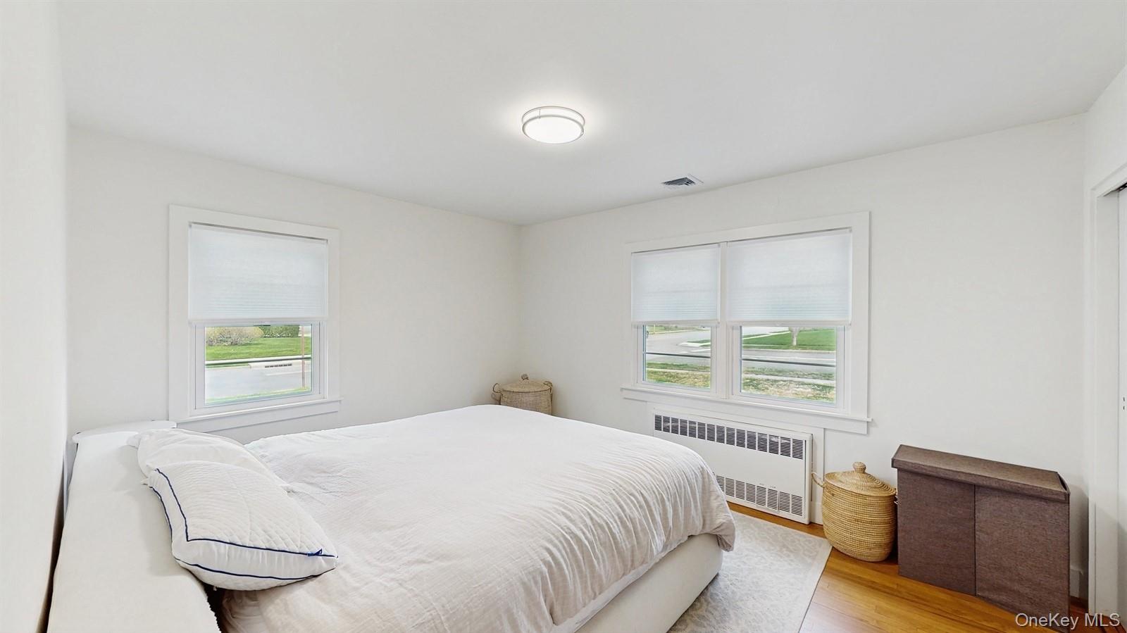 170 Wetherill Road Garden City, NY 11530 - Photo 12 of 23 Bedroom featuring visible vents, multiple windows, radiator, and wood finished floors
