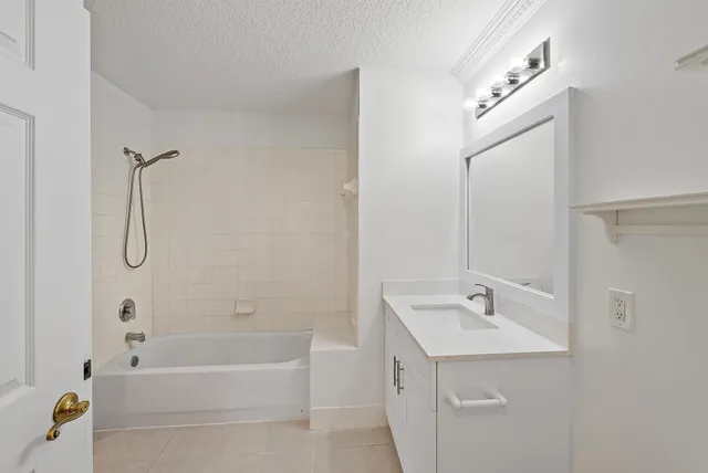 a bathroom with a tub sink vanity and mirror