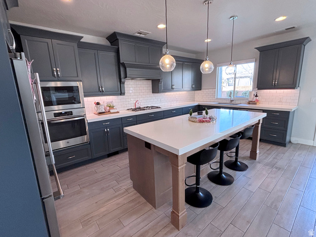 429 East Treasure Road Washington, UT 84780 - Photo 12 of 36 Kitchen featuring a breakfast bar, wood tiled floors, hanging light fixtures, and stainless steel appliances