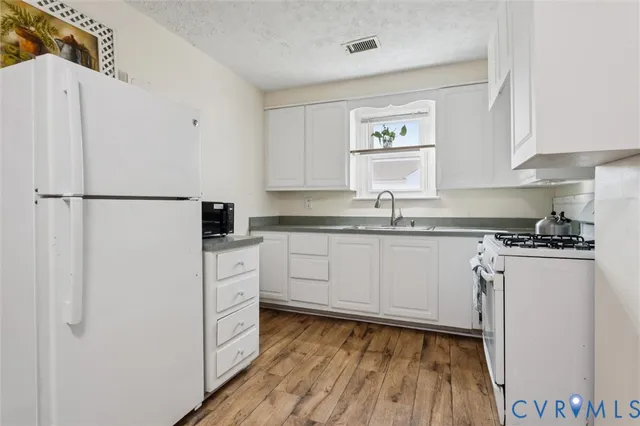 a kitchen with a refrigerator a sink and wooden floor