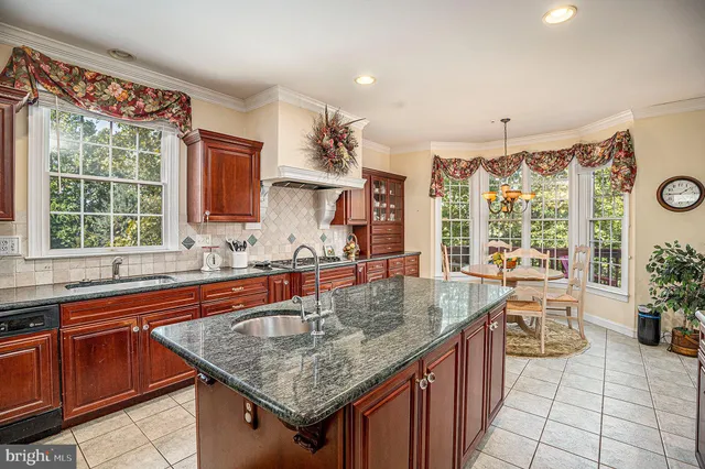 a kitchen with stainless steel appliances granite countertop a sink a counter top space and living room view