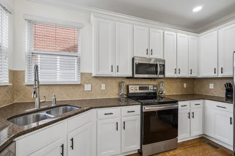 a kitchen with granite countertop white cabinets and stainless steel appliances