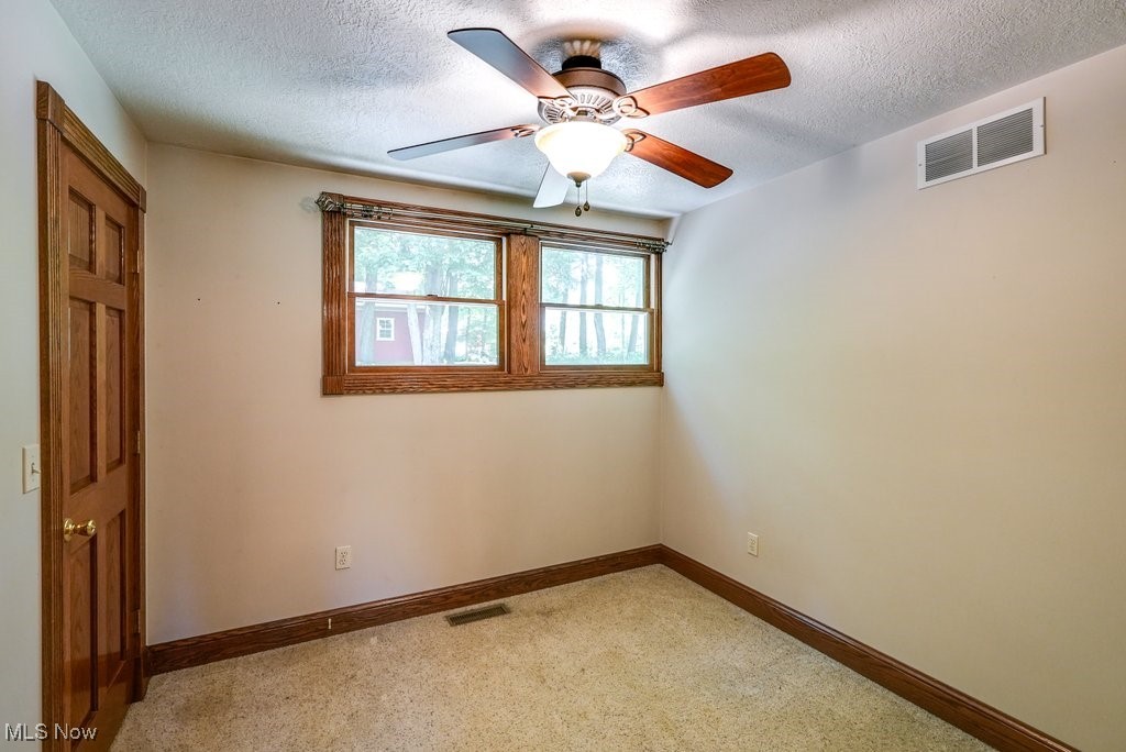 12802 Clinton Road Doylestown, OH 44230 - Photo 18 of 49 Unfurnished room featuring ceiling fan, light colored carpet, and a textured ceiling