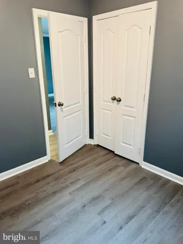 a view of a hallway with wooden floor and a bathroom