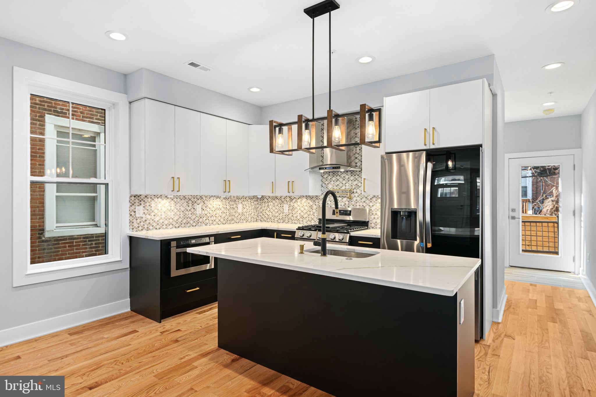 1124 Divinity Street Philadelphia, PA 19143 - Photo 7 of 37 a kitchen with kitchen island a sink stainless steel appliances and cabinets