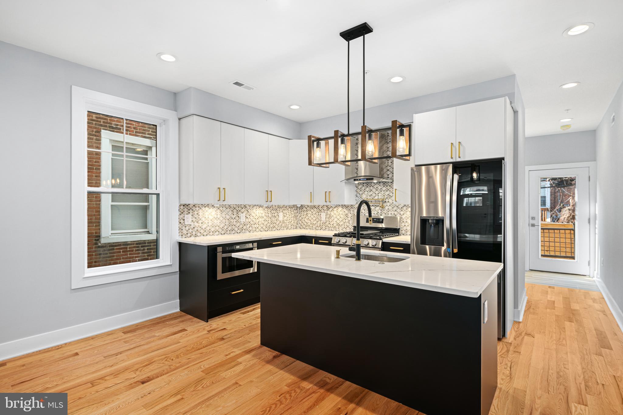 1124 Divinity Street Philadelphia, PA 19143 - Photo 8 of 37 a kitchen with stainless steel appliances granite countertop a sink a stove and a refrigerator